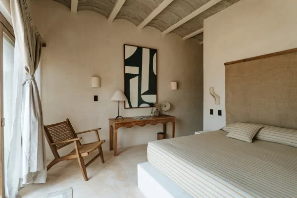 Cozy bedroom at Casa Yuma with a neutral palette and large windows overlooking the garden.