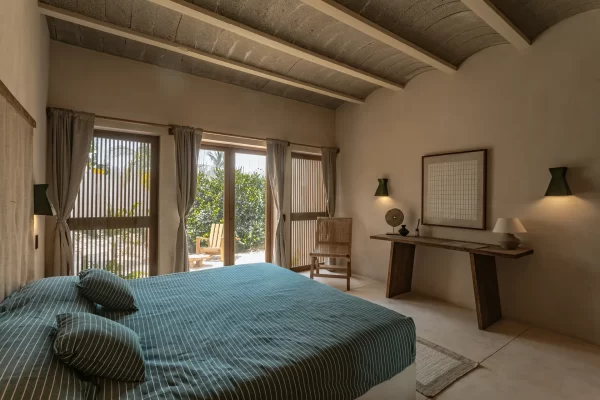 Cozy bedroom at Casa Yuma with a neutral palette and large windows overlooking the garden.